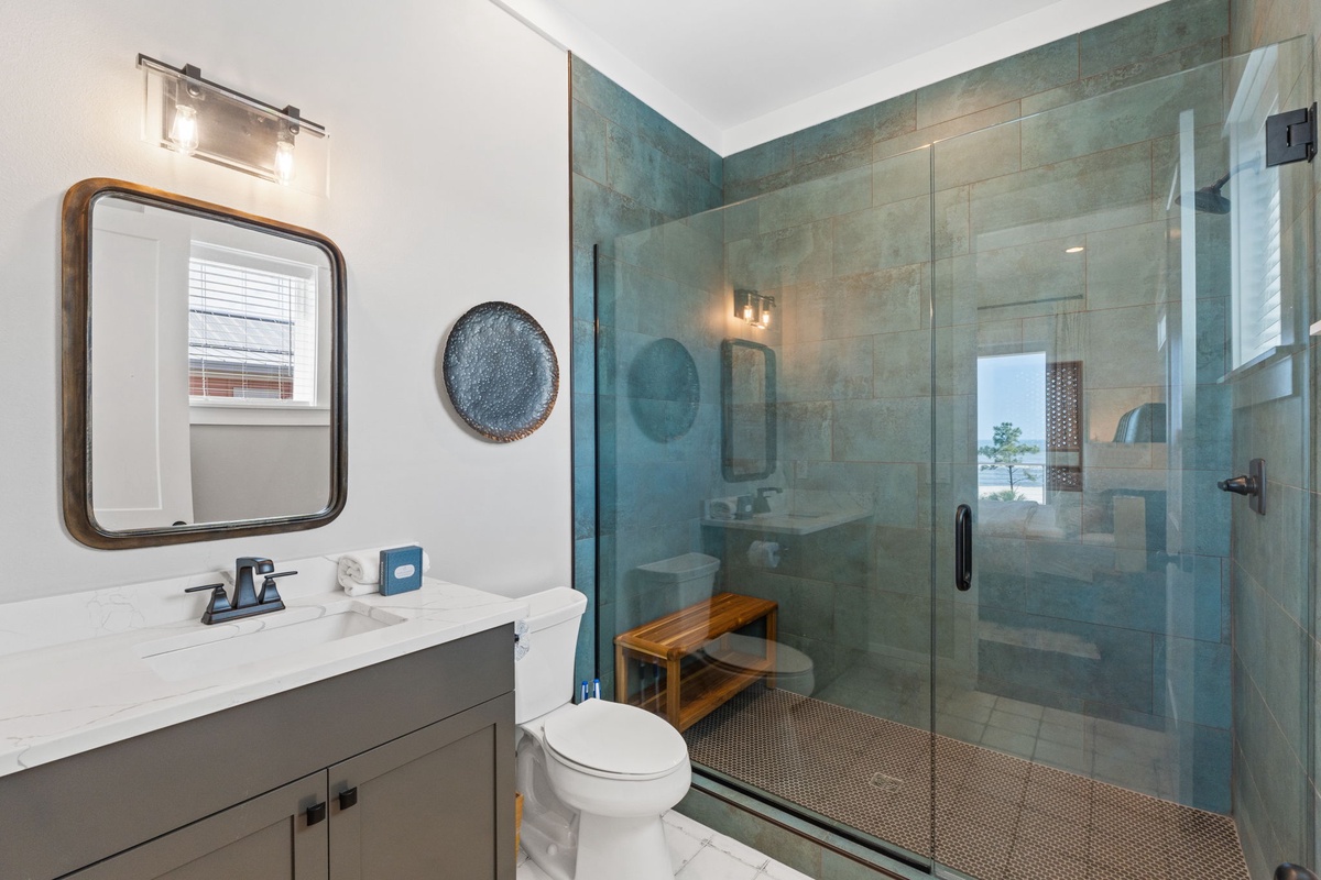 Step into your spa-like bathroom featuring a stunning walk-in shower with sea-green tiles and modern fixtures for your ultimate relaxation.