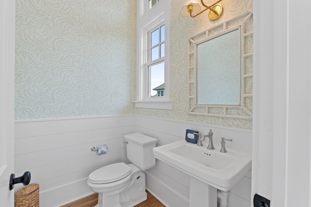 Refresh in this charming coastal-inspired bathroom with elegant shiplap, a decorative mirror, and natural light from the window.