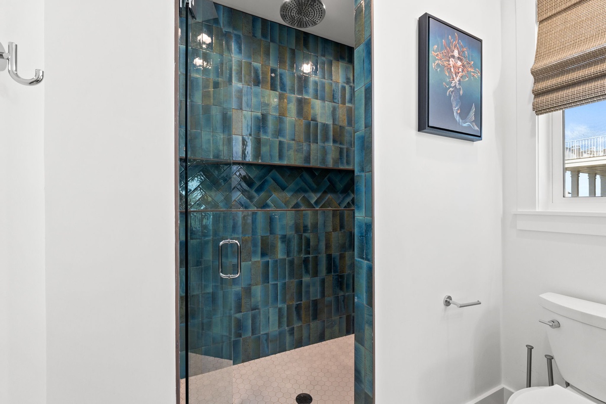 Step into your luxurious spa-like shower, featuring stunning ocean-inspired tiles in rich teal and gold, a rain showerhead, and elegant glass doors that make every morning feel like a retreat.