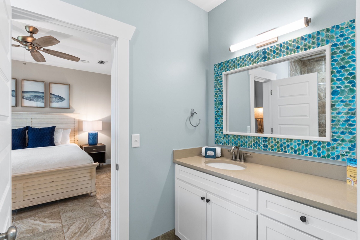 Your en-suite bathroom features soothing coastal colors and a vibrant turquoise tile accent wall that brings the beach indoors, creating your perfect seaside retreat.