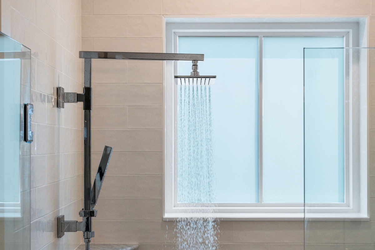Step into a spa-like shower with a luxurious rainfall showerhead and sleek modern fixtures. Natural light streams through a privacy window, making your morning routine feel refreshing and serene.
