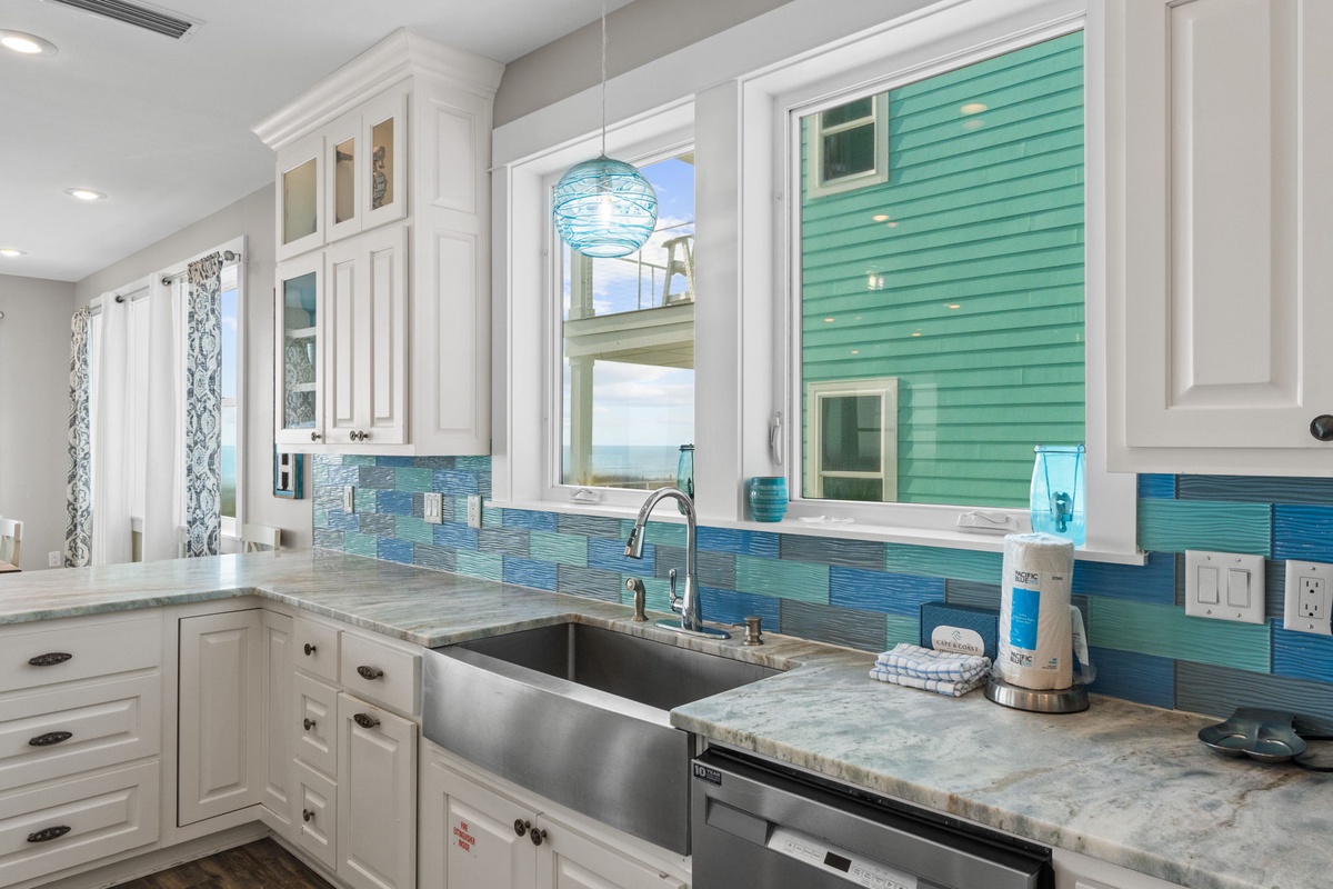 Your coastal-inspired kitchen awaits with ocean-blue tiles, white cabinets, and a farmhouse sink where you'll enjoy cooking with sea views.
