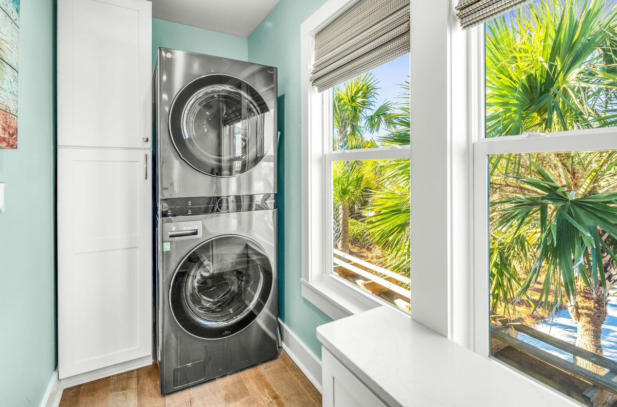 Your bright laundry nook features stacked washer and dryer with tropical views through cheerful windows.