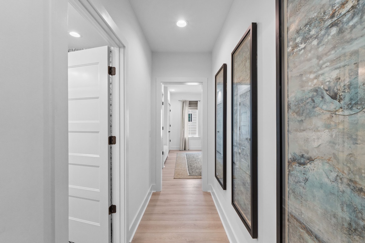 Step into this bright hallway where beautiful artwork guides your way to cozy spaces ahead.