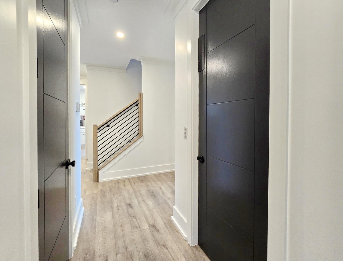 Step into your stylish hallway with warm wood floors and sleek doors leading to your private spaces.