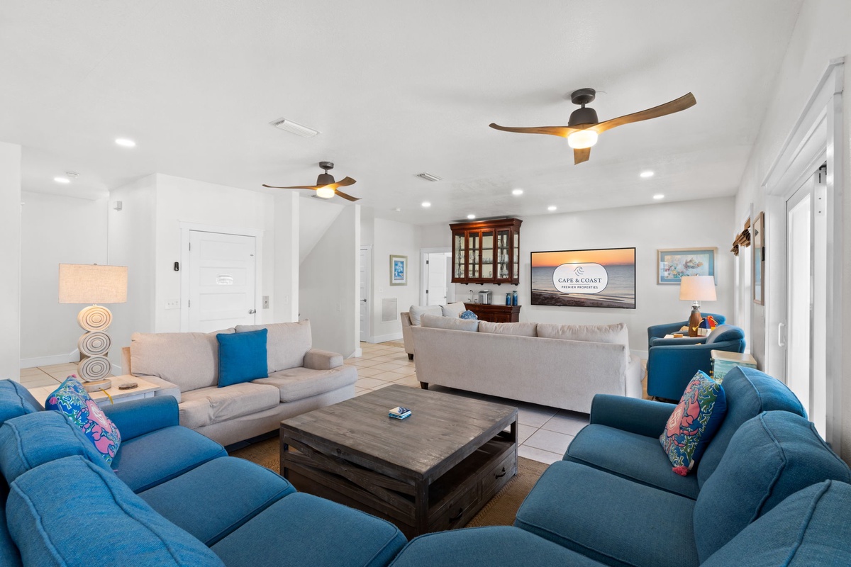 Sink into plush seating in your spacious living area, where coastal hues and modern ceiling fans create a breezy, inviting atmosphere for relaxing after a day of adventure.