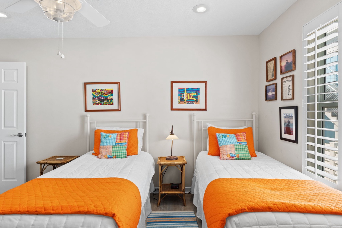 Settle into your bright twin bedroom where vibrant orange accents and colorful artwork create a cheerful retreat for restful nights.