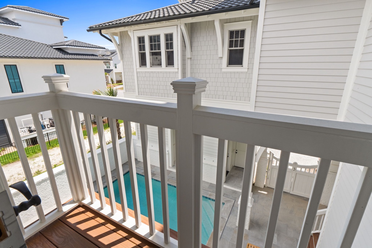 This private balcony overlooks a sparkling pool and charming courtyard, offering a peaceful spot to enjoy your morning coffee or unwind with evening views of the beautifully designed property.