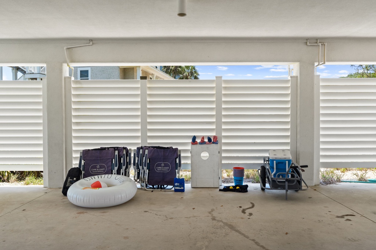 A covered garage space stocked with beach essentials—folding chairs, a cooler, inflatables, and toys—ready for your seaside adventures.