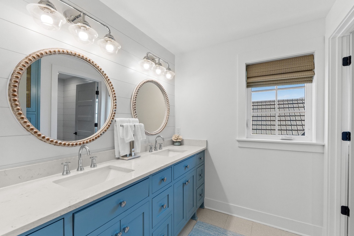 Your elegant bathroom features dual vanities with marble countertops, decorative mirrors, and bright modern lighting for your morning routine.