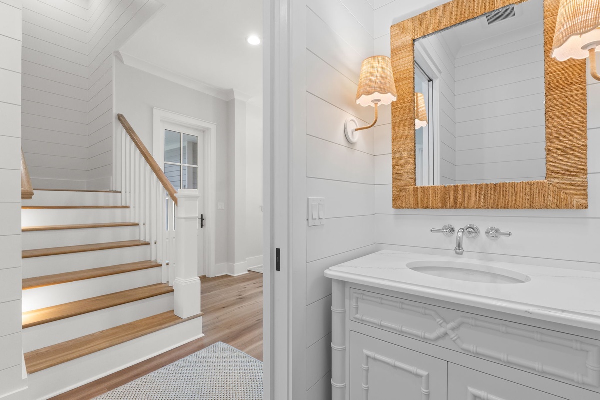 Bright coastal charm meets modern comfort in this beautifully appointed bathroom, featuring crisp white shiplap, natural woven accents, and thoughtful lighting that sets the perfect tone for your stay.