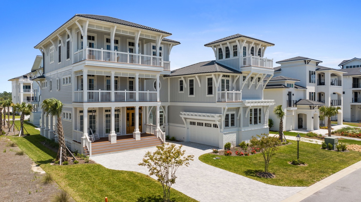 Elegant coastal-style homes featuring spacious balconies, lush landscaping, and palm-lined streets in a serene neighborhood setting.