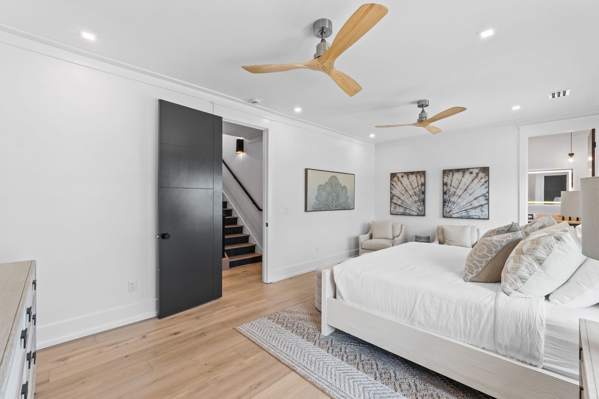 Sink into your plush king bed under whisper-quiet ceiling fans, enjoying modern coastal elegance with soft textures, warm wood floors, and a private retreat that blends comfort with style.