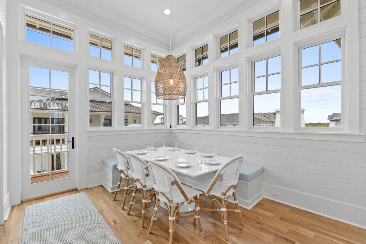 Gather around this sunlit dining nook where floor-to-ceiling windows frame neighborhood views and a cozy banquette invites you to linger over morning coffee or evening meals together.