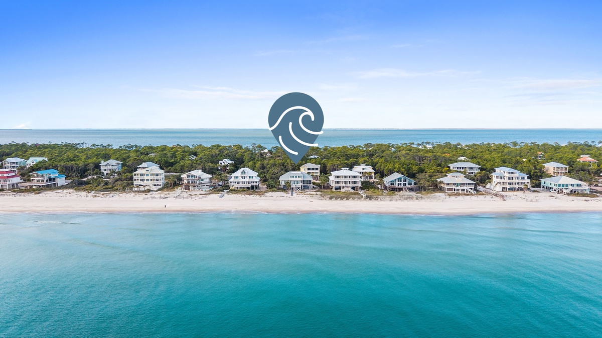 Stunning beachfront properties line pristine white sand beaches along crystal-clear turquoise waters under endless blue skies.