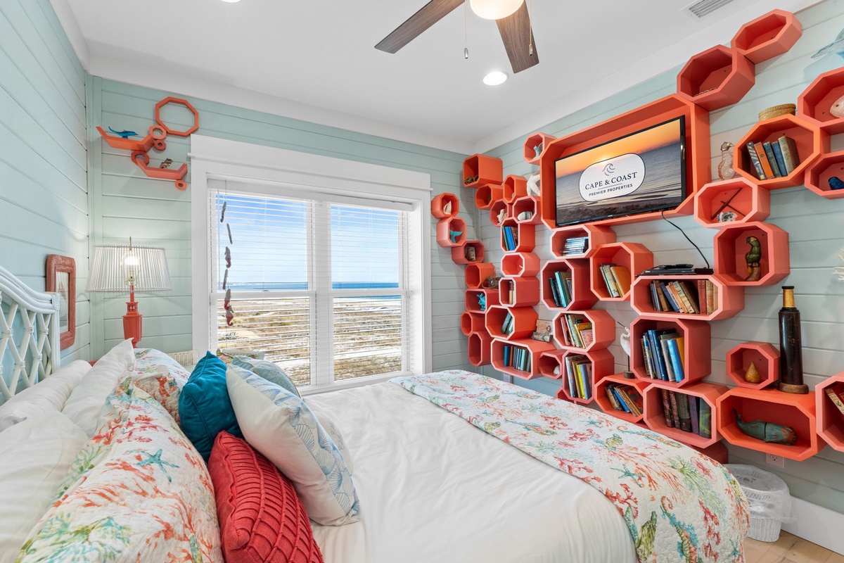 Wake up to stunning coastal views in this playful bedroom featuring vibrant orange honeycomb shelving and soothing seaside colors.