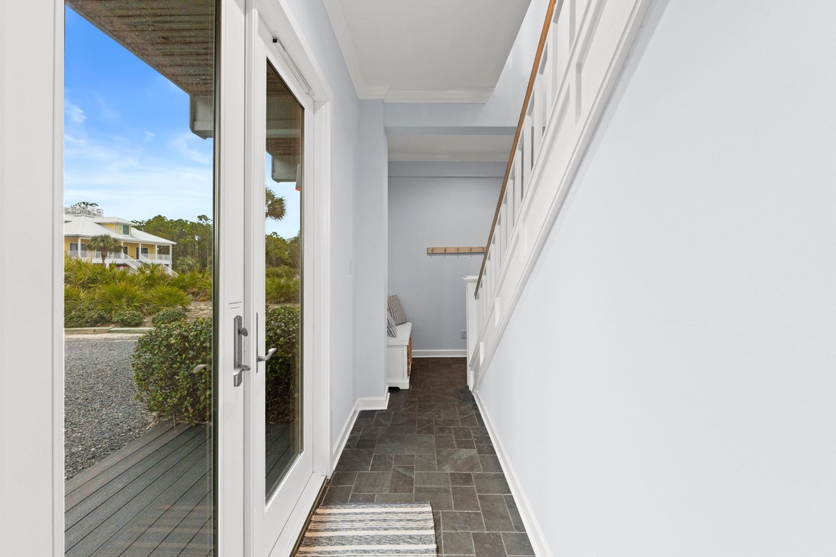Step into your bright entryway where natural light floods through glass doors, revealing garden views and clean modern design.
