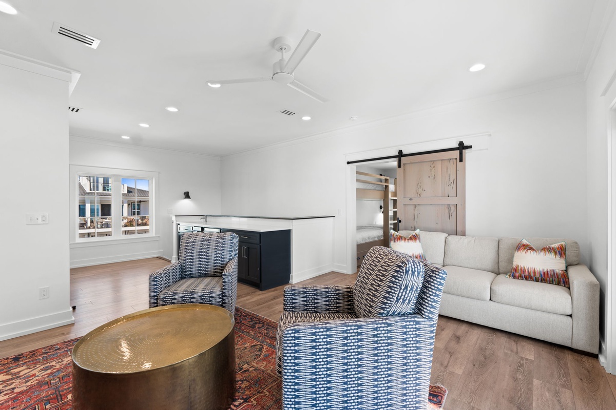 Relax in your bright, modern living space featuring stylish seating, rustic barn door accents, and an open kitchen perfect for entertaining.