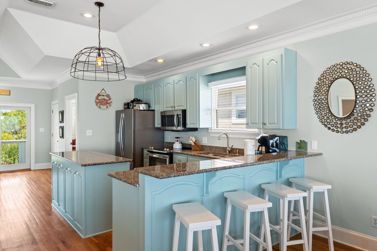 Your bright coastal kitchen awaits with charming aqua cabinets, granite countertops, and a breakfast bar perfect for morning coffee.