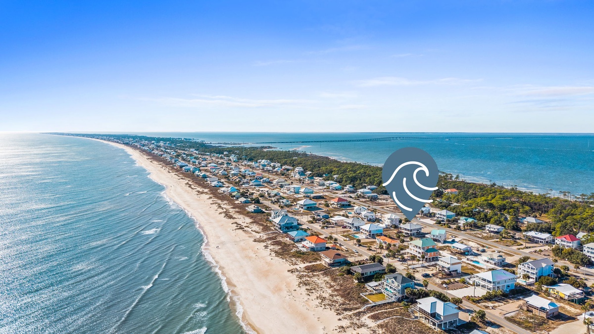 Stunning aerial perspective of the pristine coastline and charming beachfront community surrounding the property area.