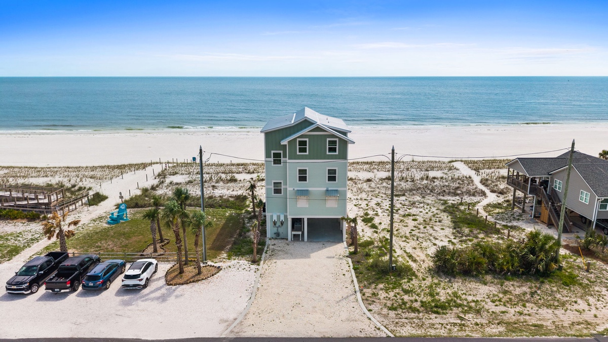 Beachfront property situated directly on white sandy shores with panoramic ocean views, offering immediate beach access and ample parking for guests.