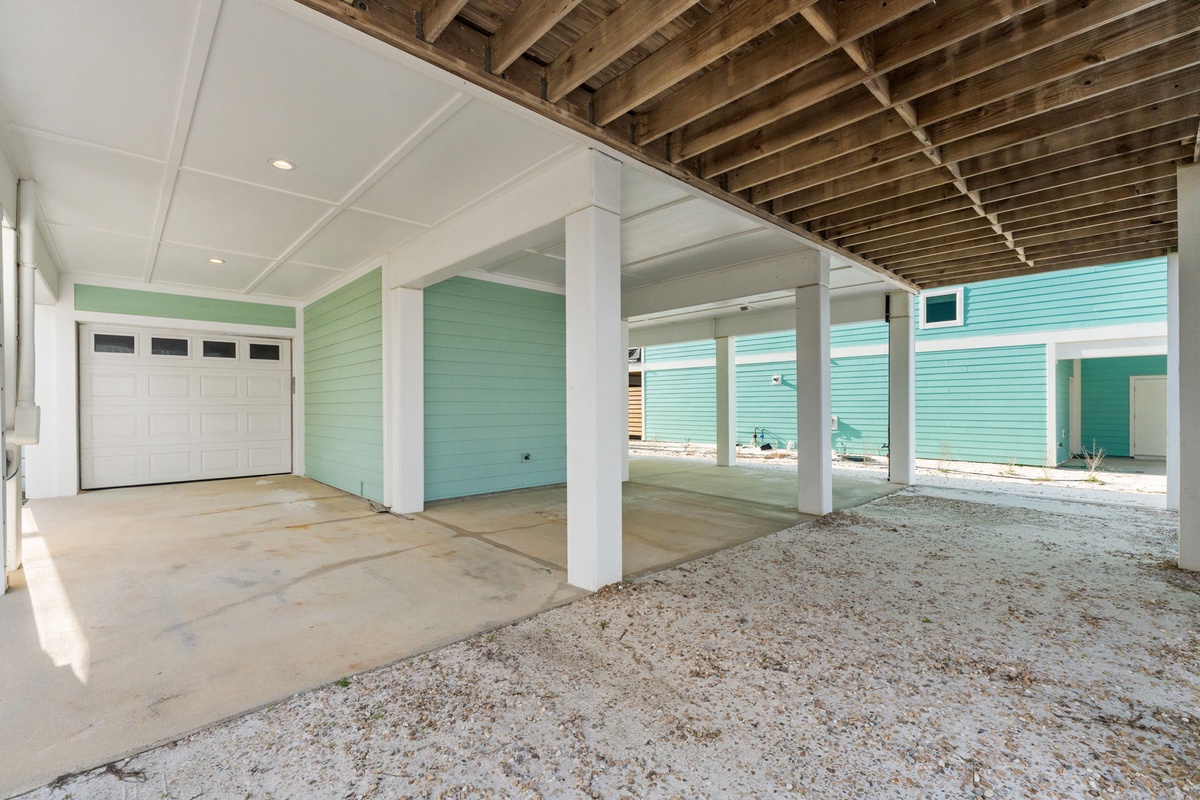 Spacious covered parking with exposed beam ceiling offers protection for your vehicles and beach gear storage.