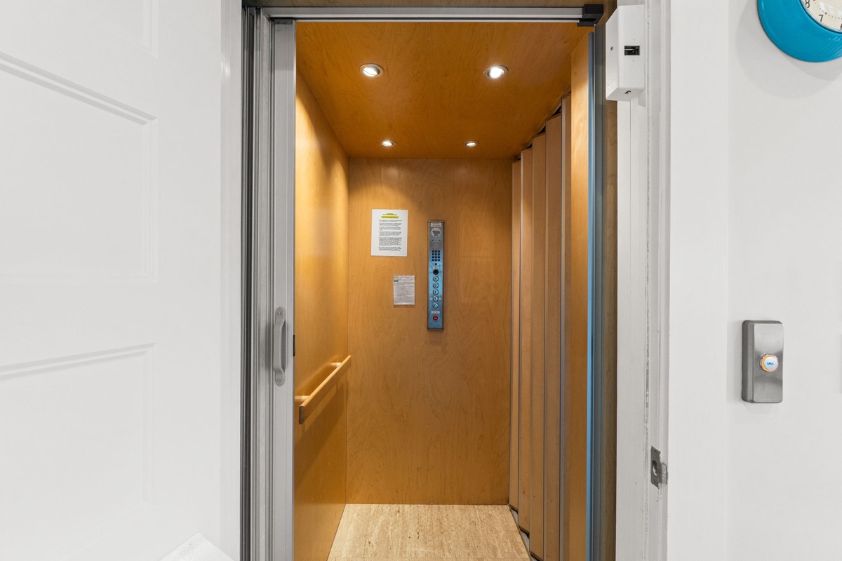 Step into the modern elevator with warm wood paneling and bright lighting for easy access to your floor.