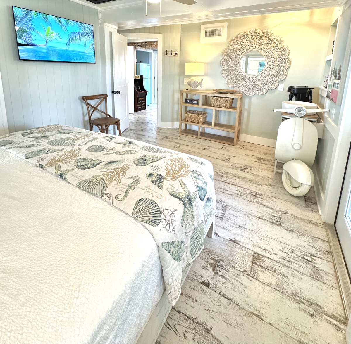 Drift off in your coastal sanctuary, where ocean-themed bedding meets warm wood floors and tropical TV views create perfect relaxation.