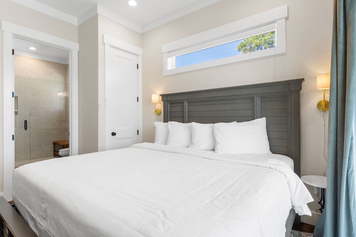 Rest in your serene bedroom featuring crisp white linens, elegant gray headboard, and warm sconces for reading.