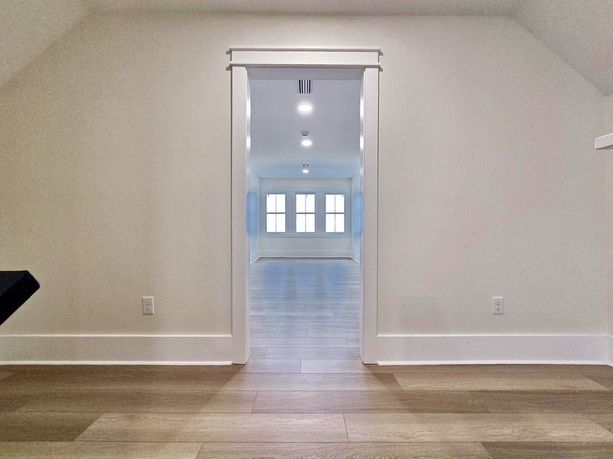 Step into your spacious, light-filled sanctuary with gleaming hardwood floors and elegant archway leading to bright windows.