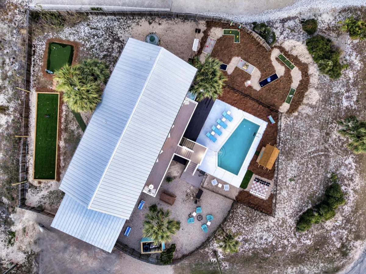 Aerial view of Island Days with a large fenced yard, swimming pool, miniature golf, bocce ball court, and putting green.