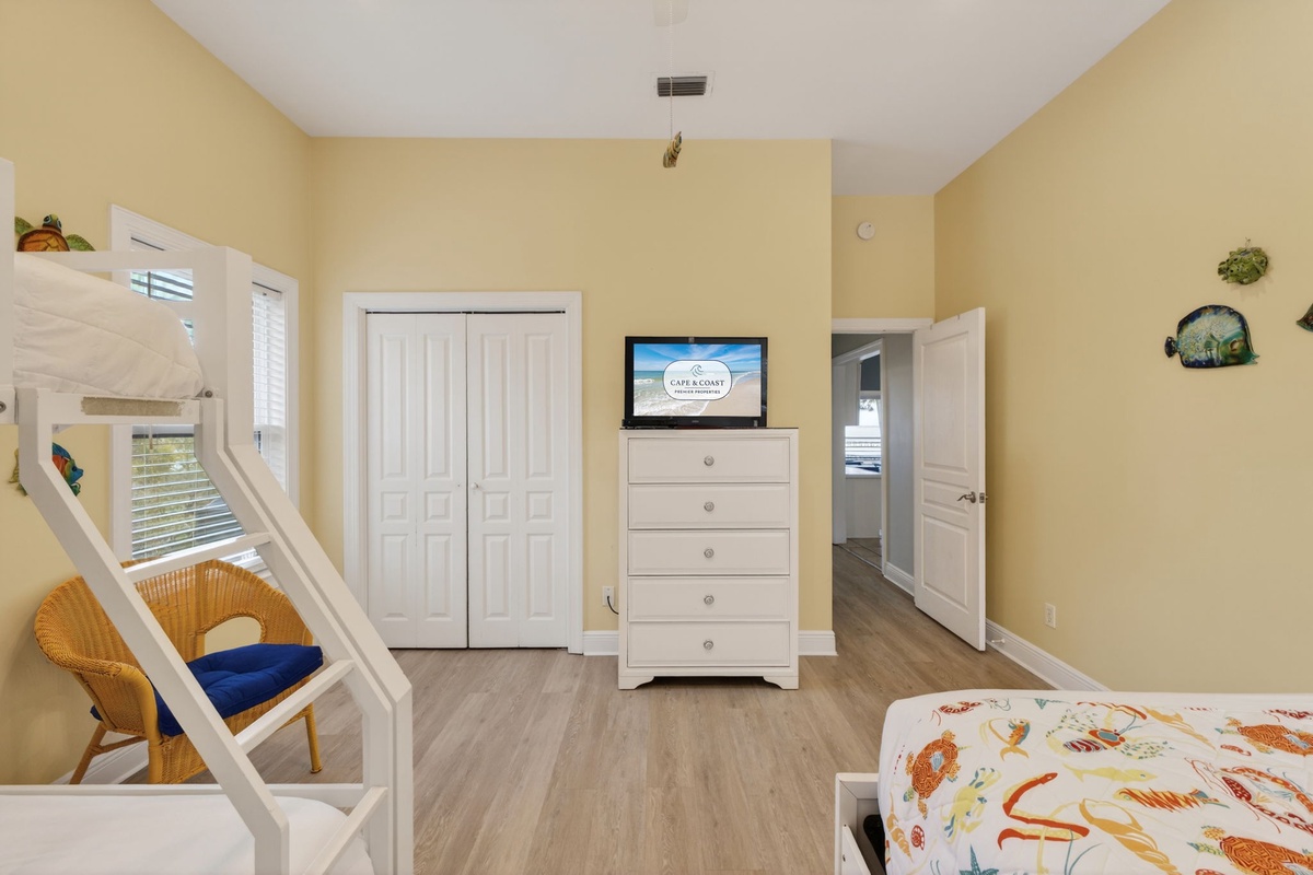 Your bright family bedroom features custom bunk beds, warm yellow walls, and entertainment center perfect for movie nights together.