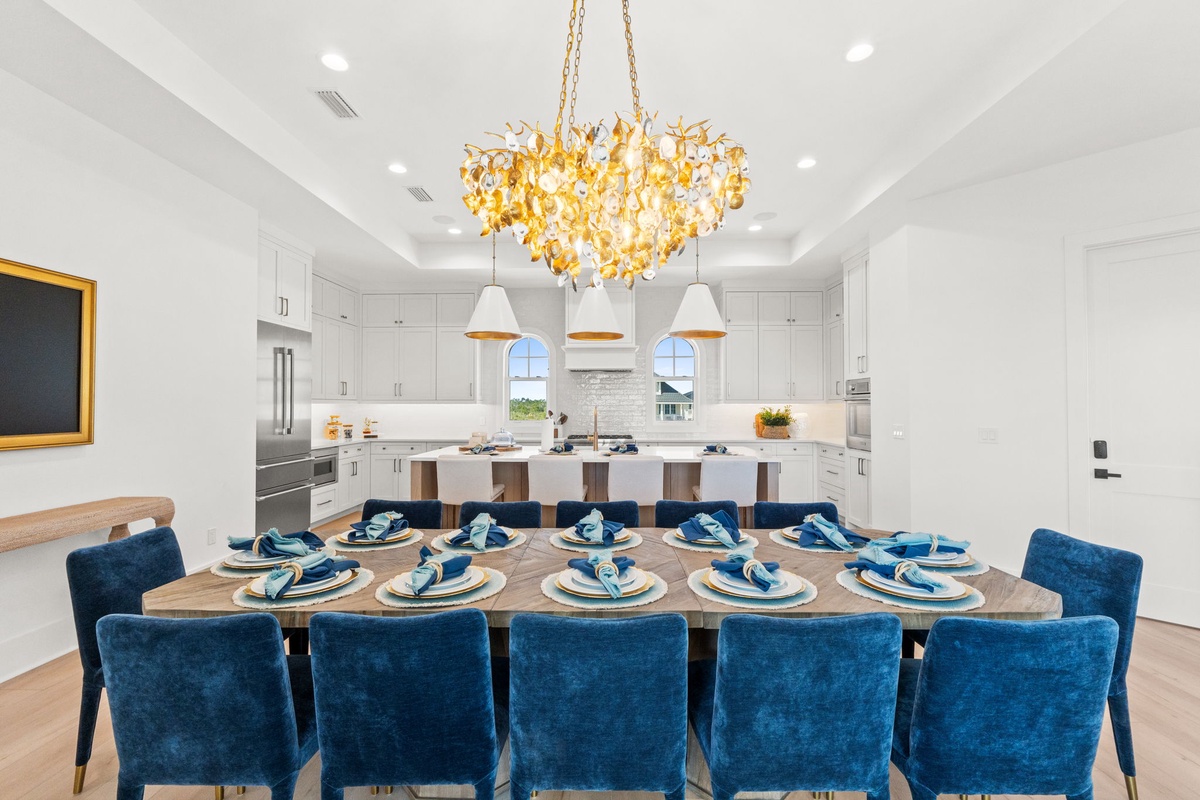 Gather around this elegant dining table where meaningful conversations flow beneath a stunning golden chandelier in your open-concept space.