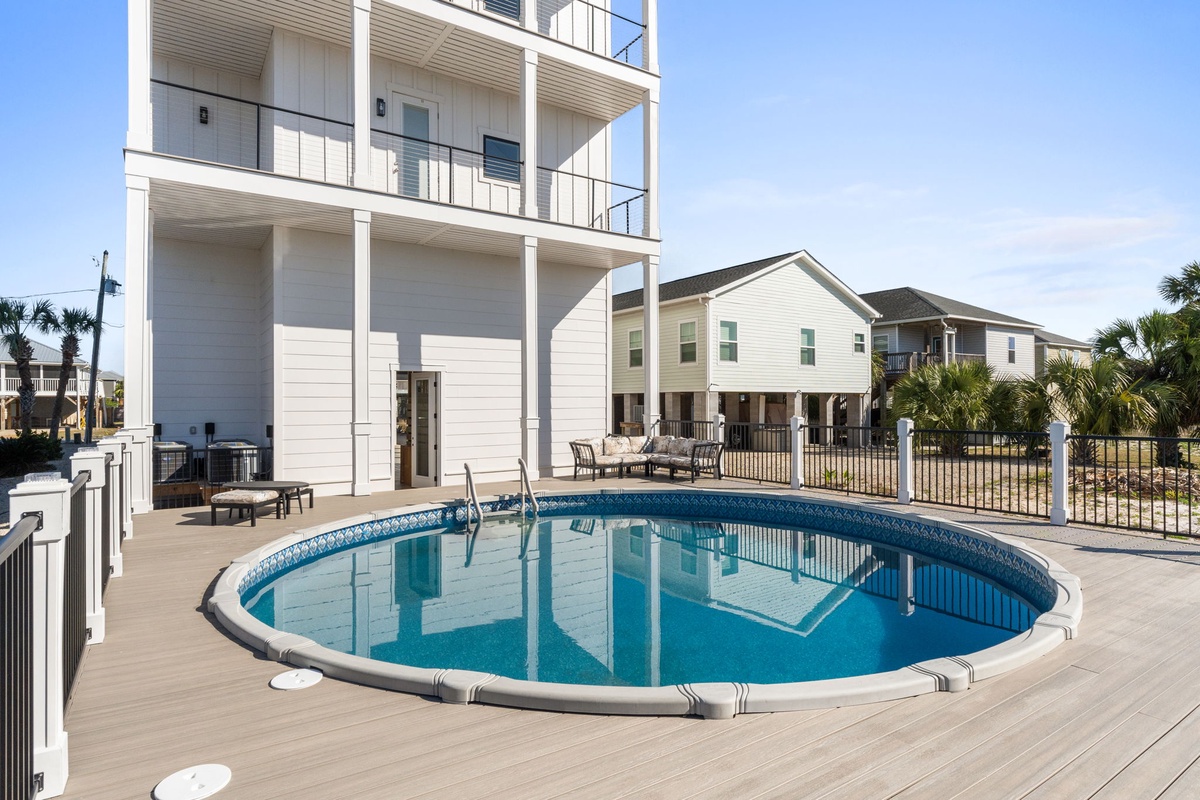 Your private oasis awaits with a sparkling pool perfect for cooling off after beach days, surrounded by spacious decking for lounging.