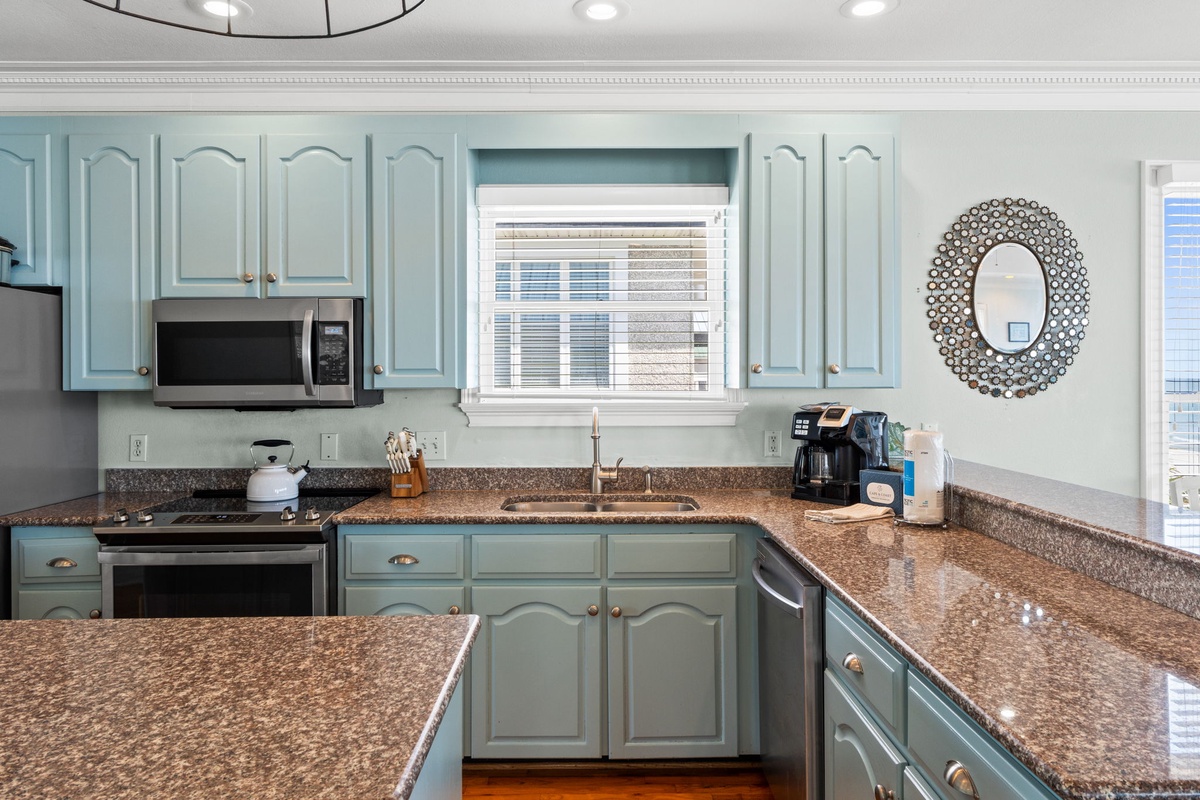 Your fully equipped kitchen features beautiful sage-green cabinets, granite countertops, and modern appliances—perfect for preparing meals during your stay.