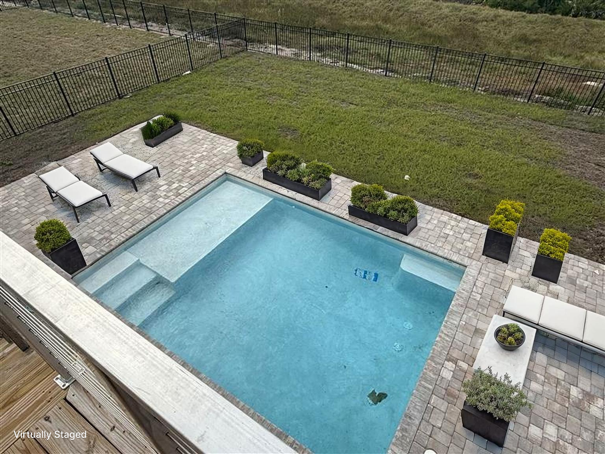 Aerial view of the property's beautiful swimming pool area with elegant paver deck and landscaping.