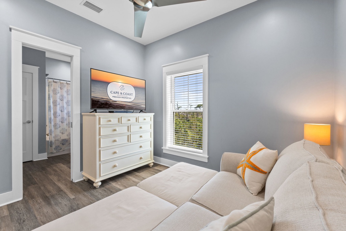 Unwind in your peaceful bedroom with calming blue walls, cozy seating, and entertainment ready for your relaxation.