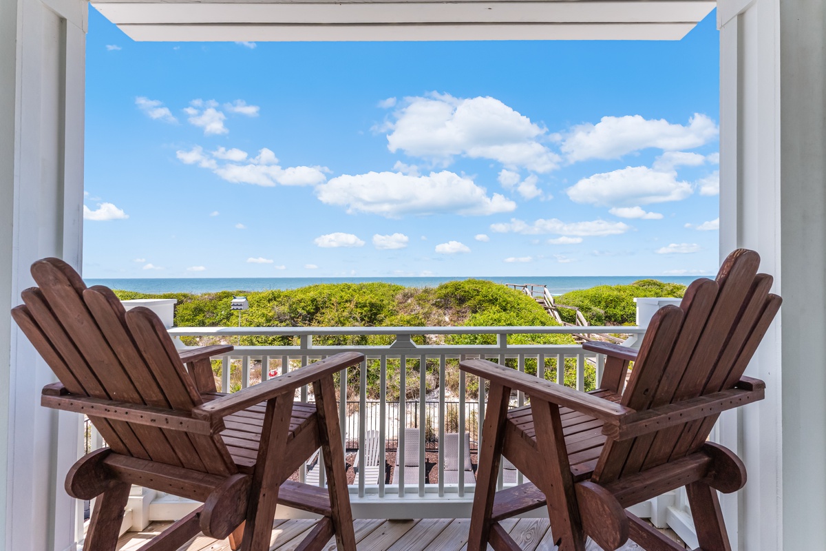 Two Adirondack chairs await on your private balcony, offering peaceful ocean views and coastal breezes.