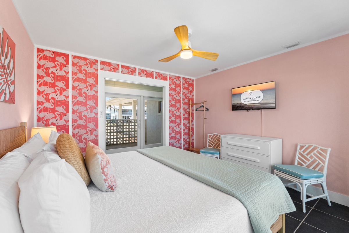 Drift off to sleep in this playful bedroom with flamingo wallpaper, warm tropical vibes, and a private view to your balcony beyond.