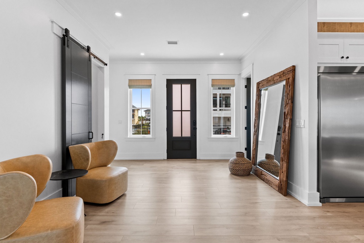 Step into your bright and airy entryway where natural light pours through elegant windows. A stylish barn door and cozy seating greet you, setting a warm tone for your stay.