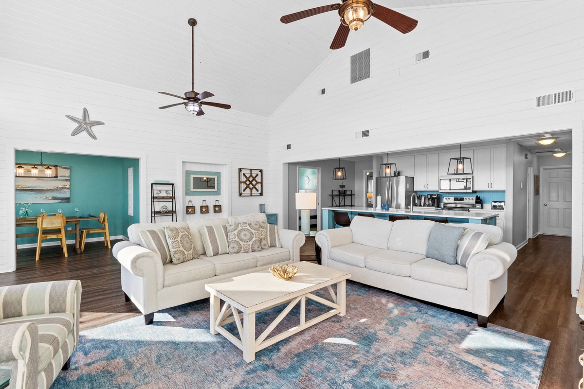 Sink into plush seating in this open-concept space where coastal charm meets modern comfort, complete with vaulted ceilings and ocean-inspired decor.