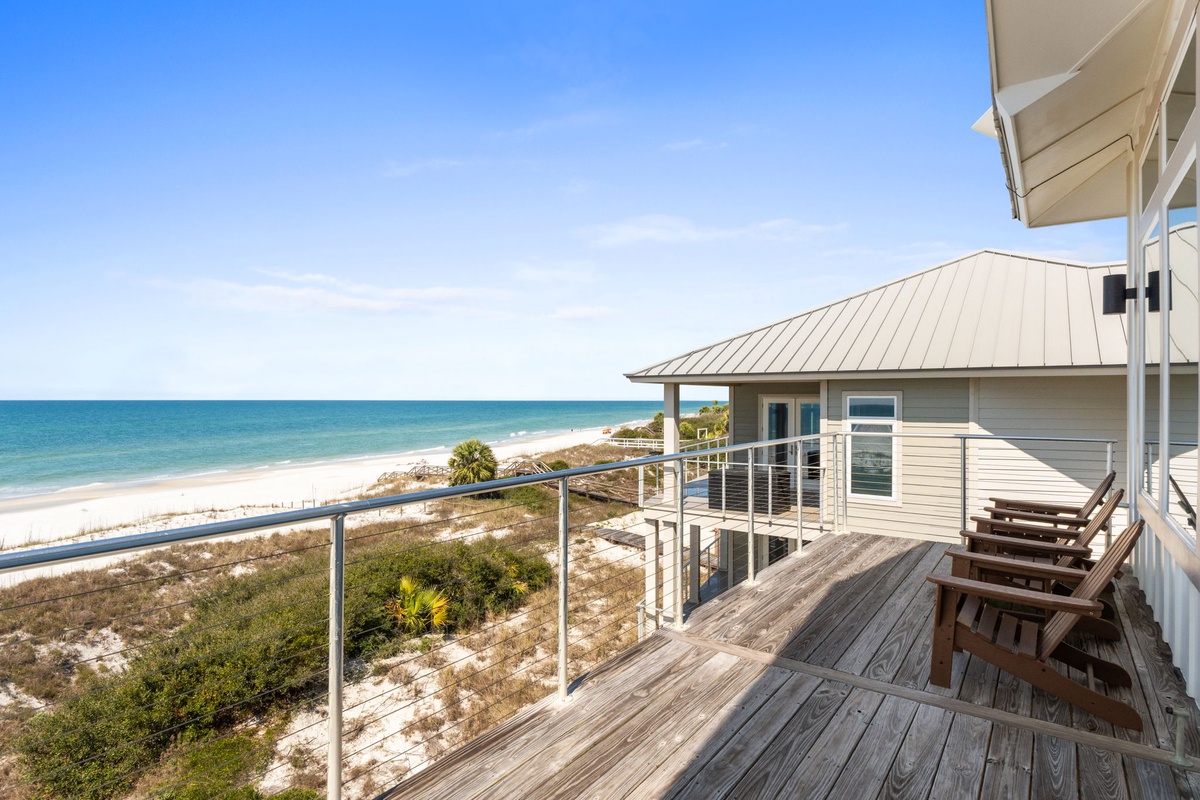 Beachfront property balcony offers stunning ocean views with direct beach access and outdoor seating areas.