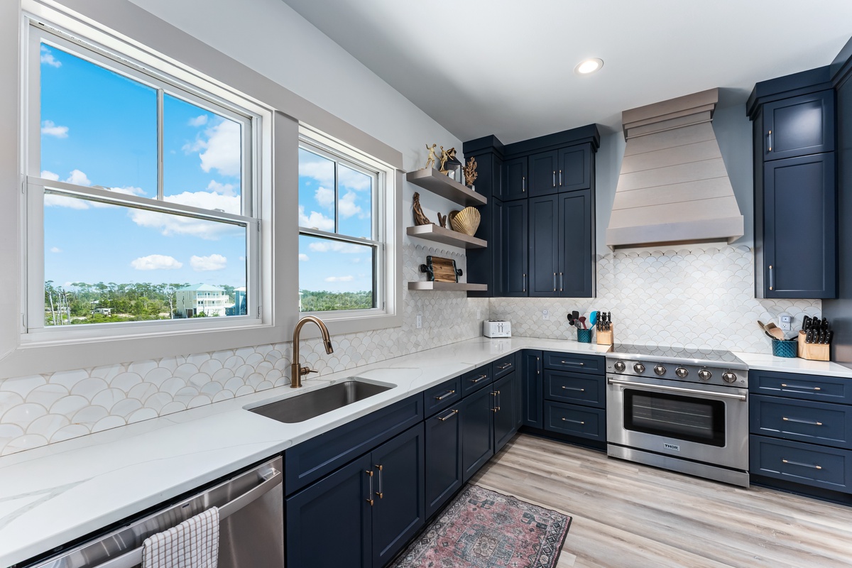 Your modern kitchen features elegant navy cabinetry and marble countertops, perfect for preparing meals while enjoying natural light.