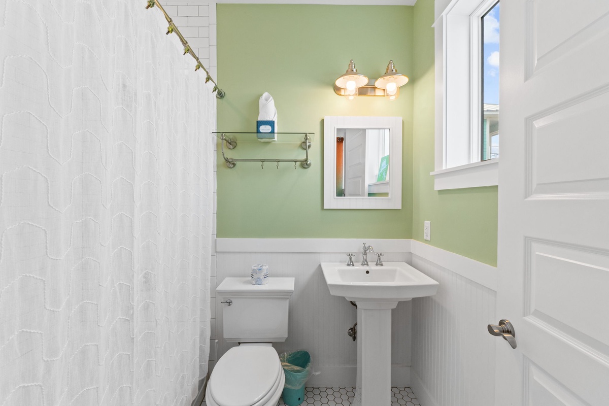 Refresh in your bright, clean bathroom with thoughtful touches like a glass shelf and warming green accent wall.