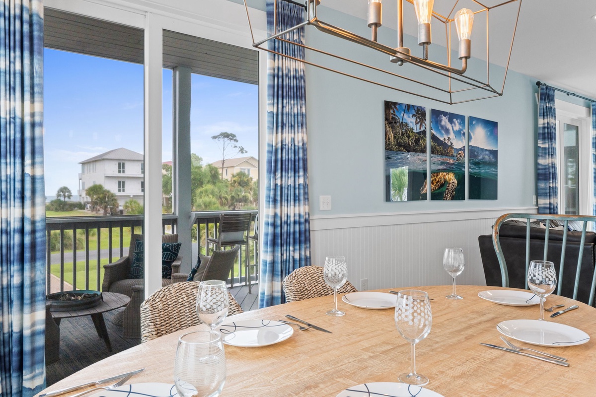 Gather around your dining table set for a delicious meal, with coastal artwork above and a private balcony inviting you to enjoy the lush greenery views.