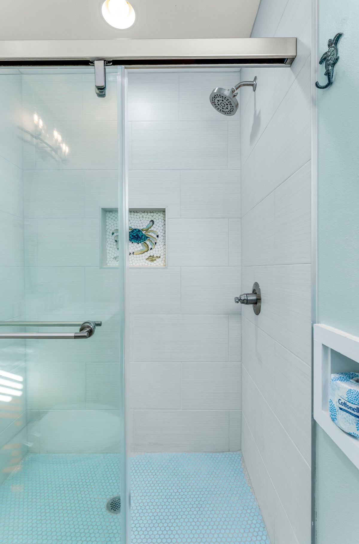 Step into your sleek glass-enclosed shower with modern fixtures and soothing coastal-inspired tiles.
