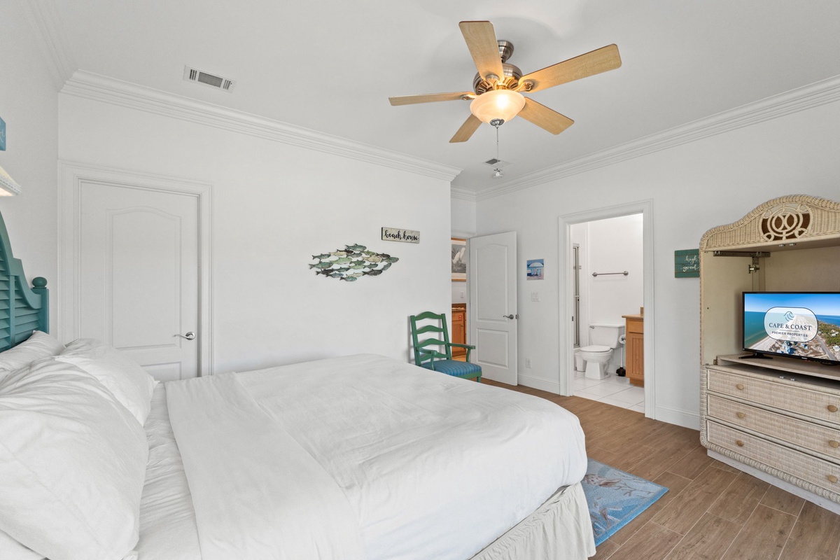 Relax in your coastal retreat with crisp white linens, beach-themed décor, ceiling fan, and an ensuite bathroom for your comfort.
