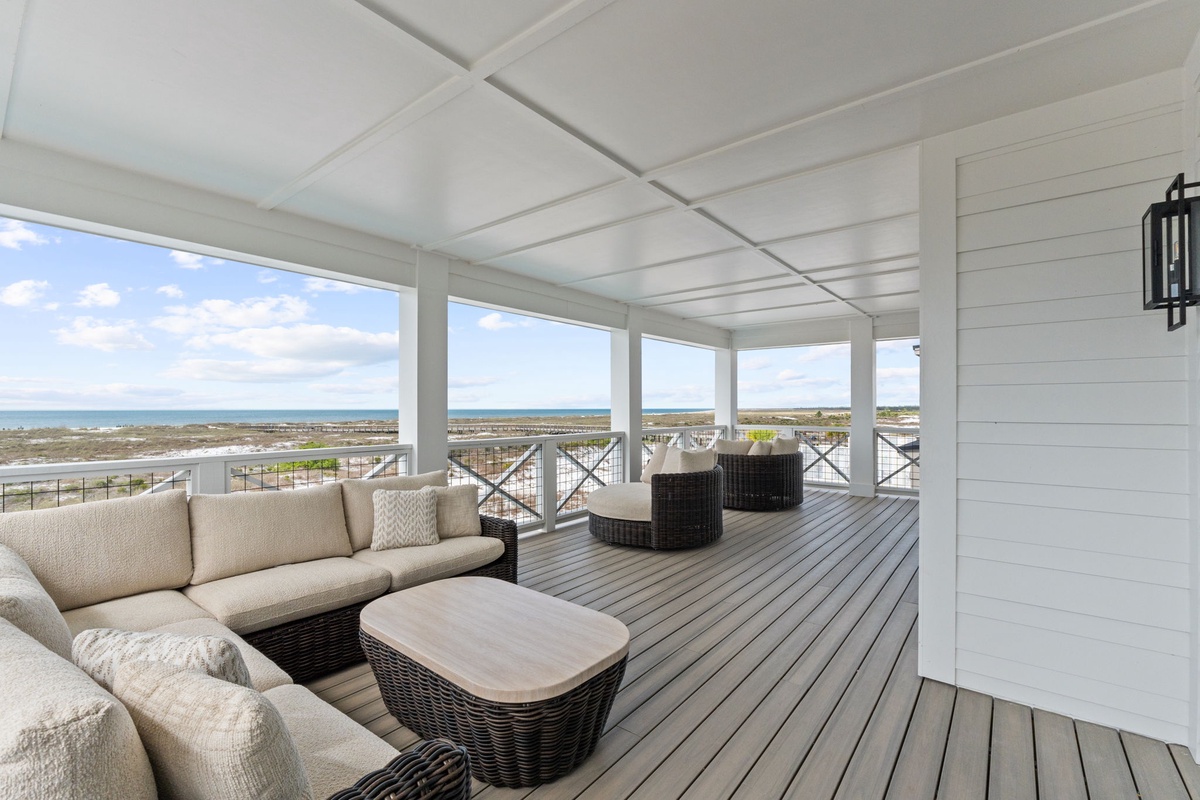 Your covered deck sanctuary offers plush seating where you can unwind while gazing at endless ocean views through elegant railings.