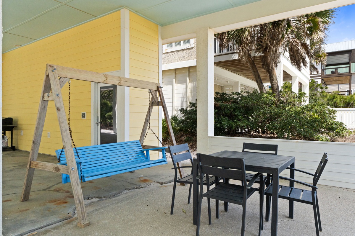 Relax on your private patio with a charming swing and outdoor dining space, surrounded by tropical palms and coastal charm.