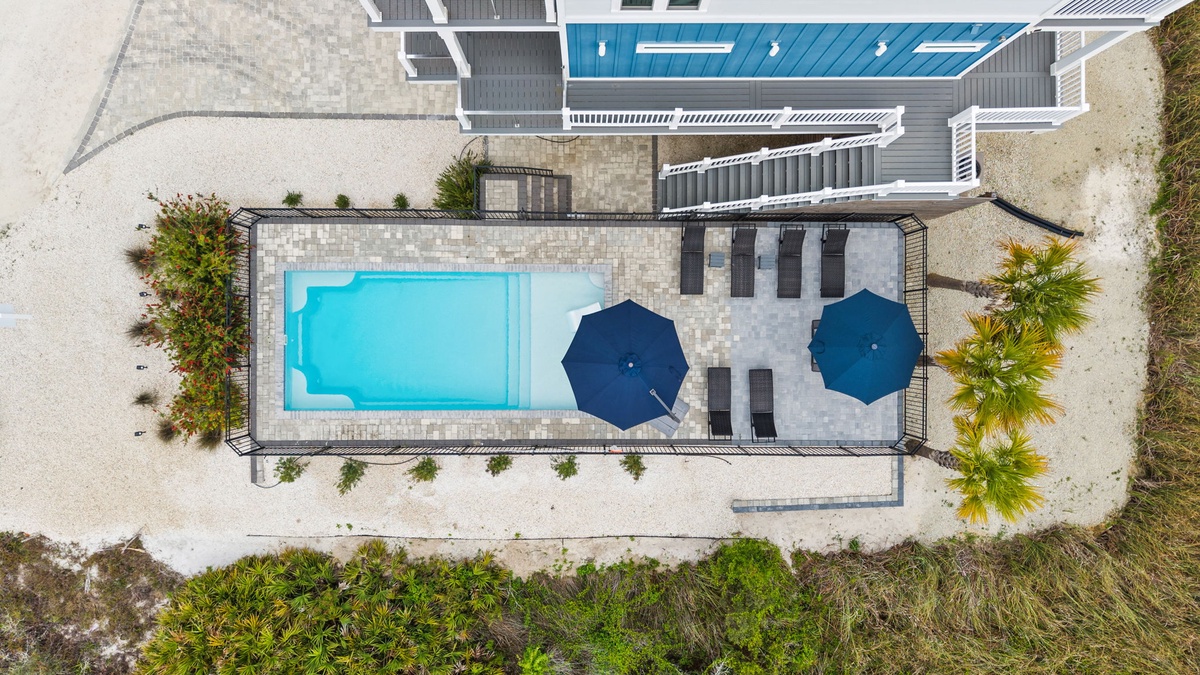 Modern vacation rental with crystal-clear pool and covered lounging area surrounded by tropical landscaping.